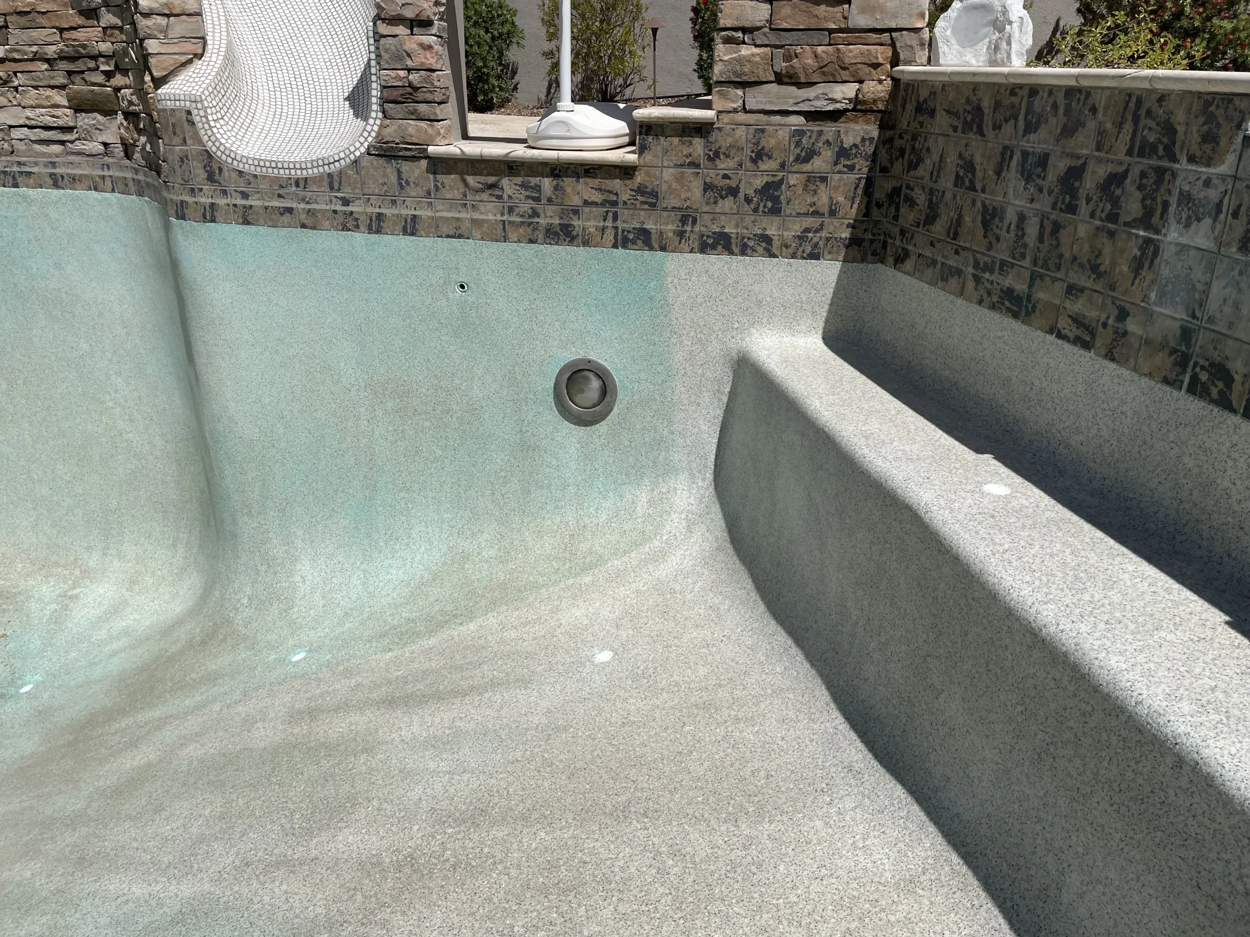 Signs of pool deterioration including rough plaster and calcium buildup, highlighting the need for remodeling